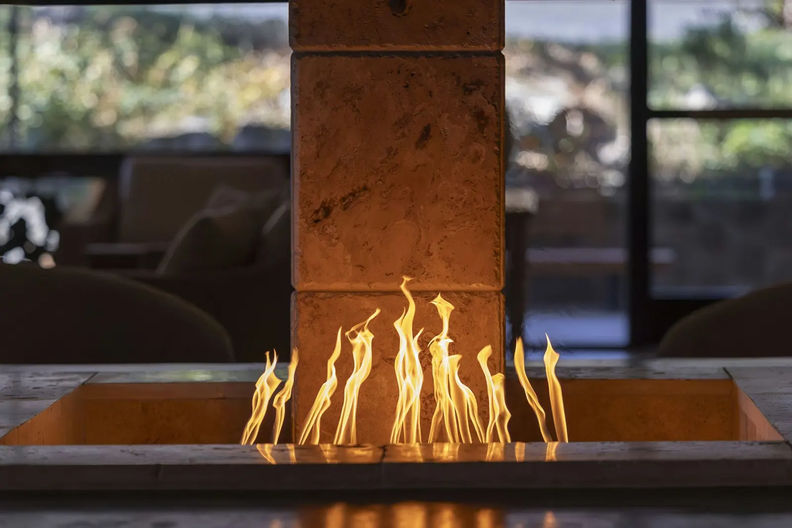 Gas fire feature in a desert home, with rock hills outside the windows
